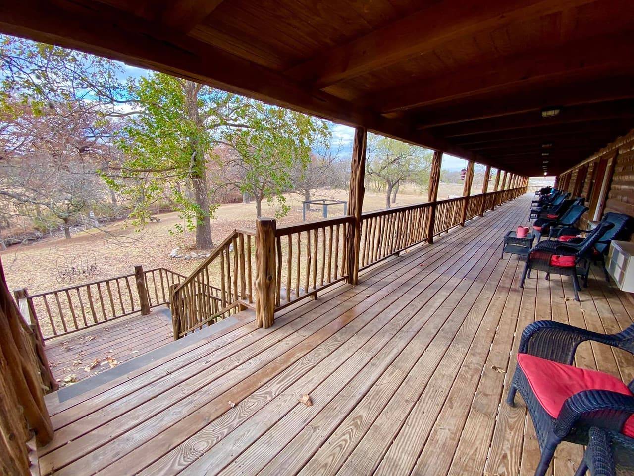 Long covered porch at Sabinal River Lodge lined with wicker rocking chairs overlooking the grounds