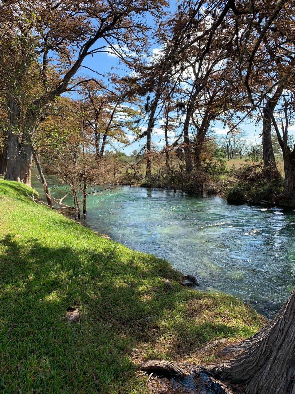 A bend in the Sabinal River with clear blue-green water winding through wooded banks