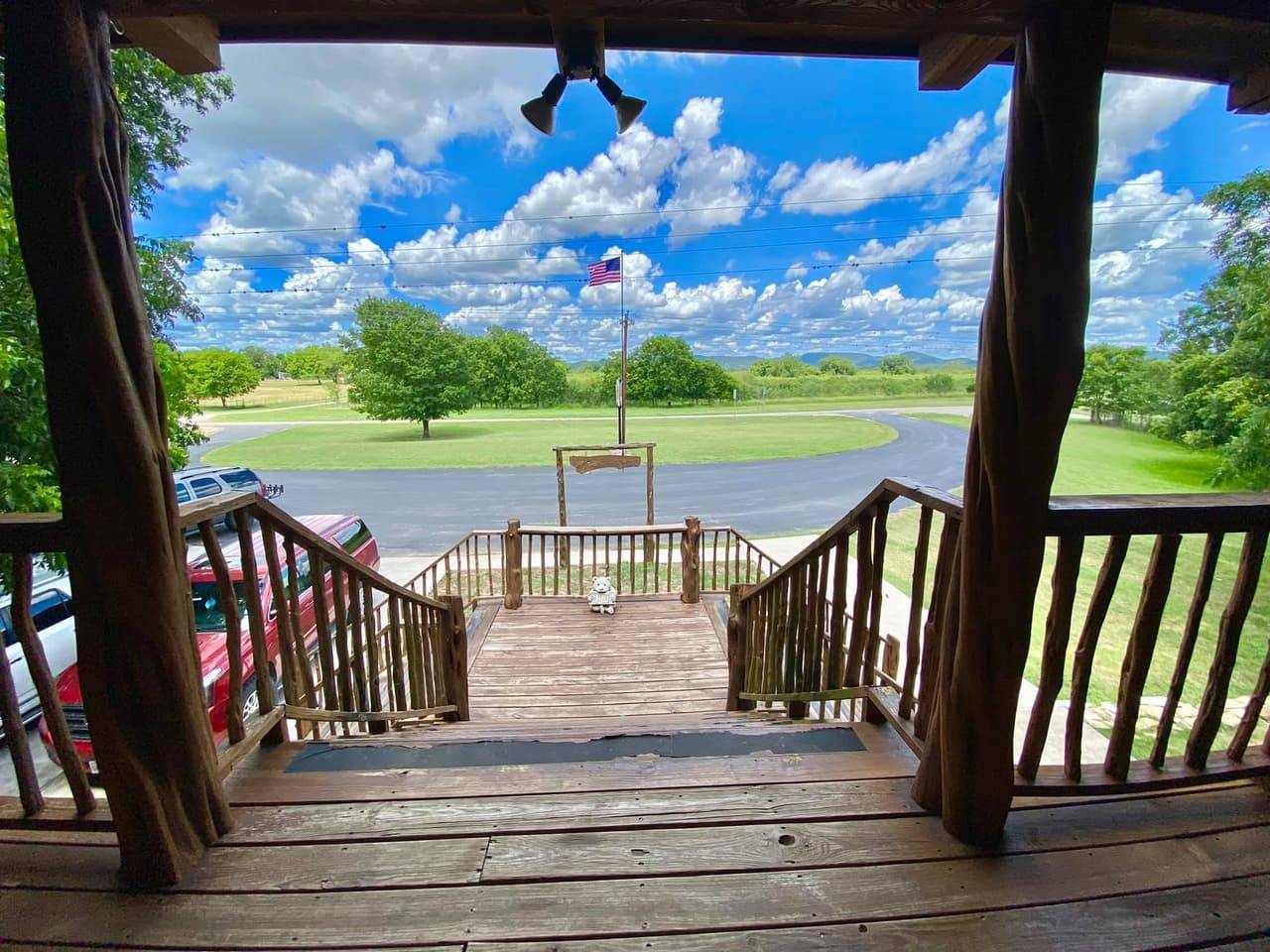 View down the lodge's covered deck stairs toward the parking area with a U.S. flag flying