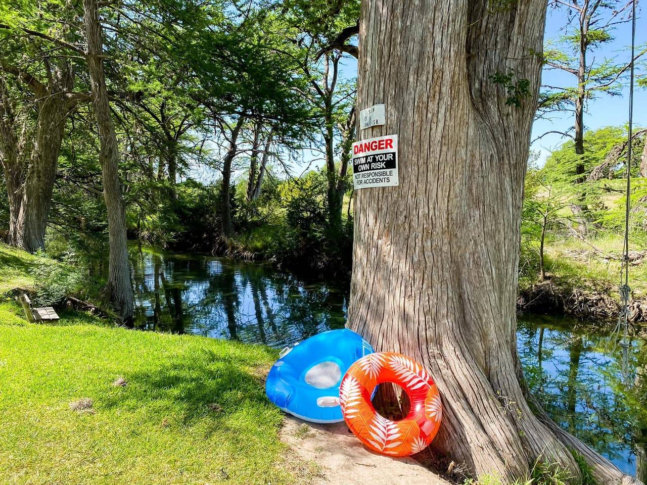 Inflatable river tubes leaning against a cypress tree on the Sabinal River