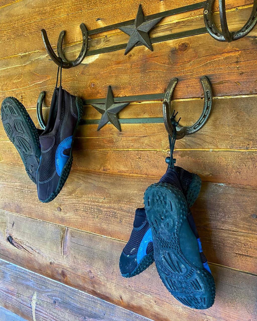 Rustic horseshoe and star wall hooks holding water shoes ready for the river