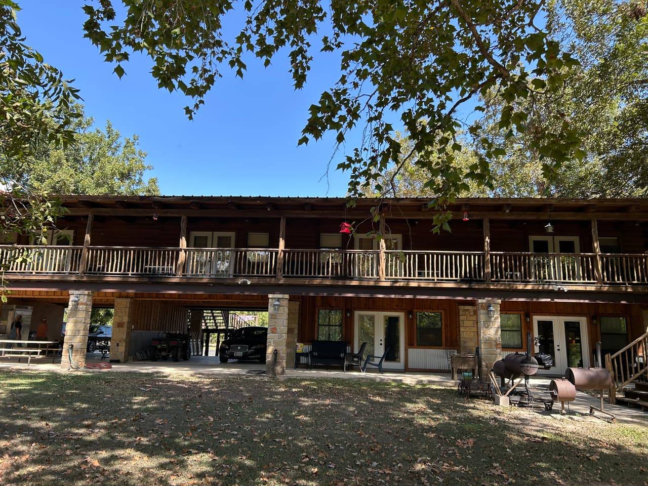 Two-story lodge building with covered porches and decks overlooking the shaded lawn