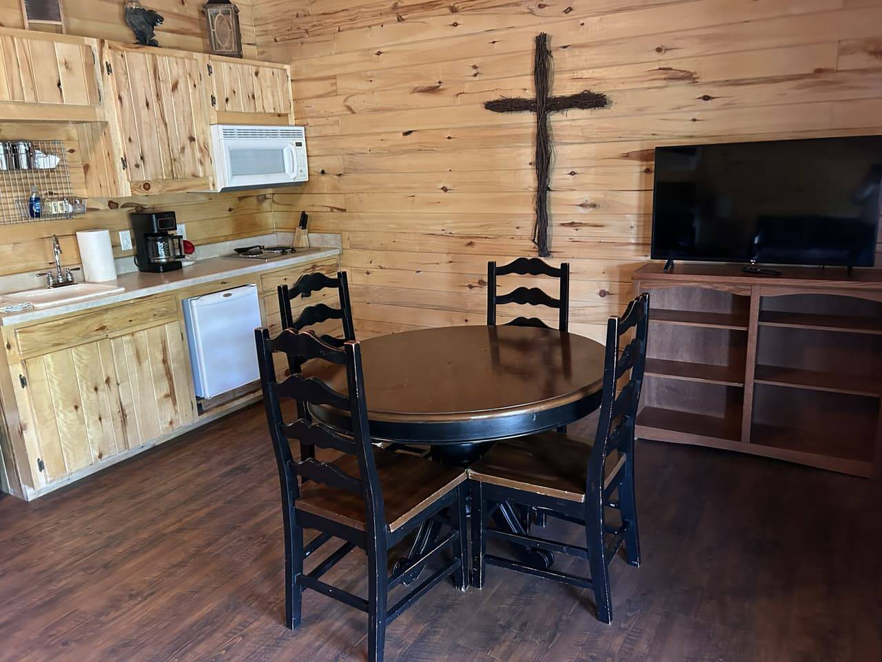 Log-style dining nook with a round table, four chairs, and a wall-mounted TV
