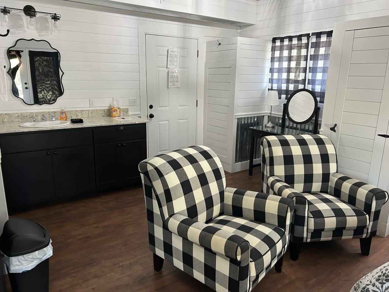 Sitting nook with black vanity cabinet and two buffalo-check armchairs against white shiplap walls