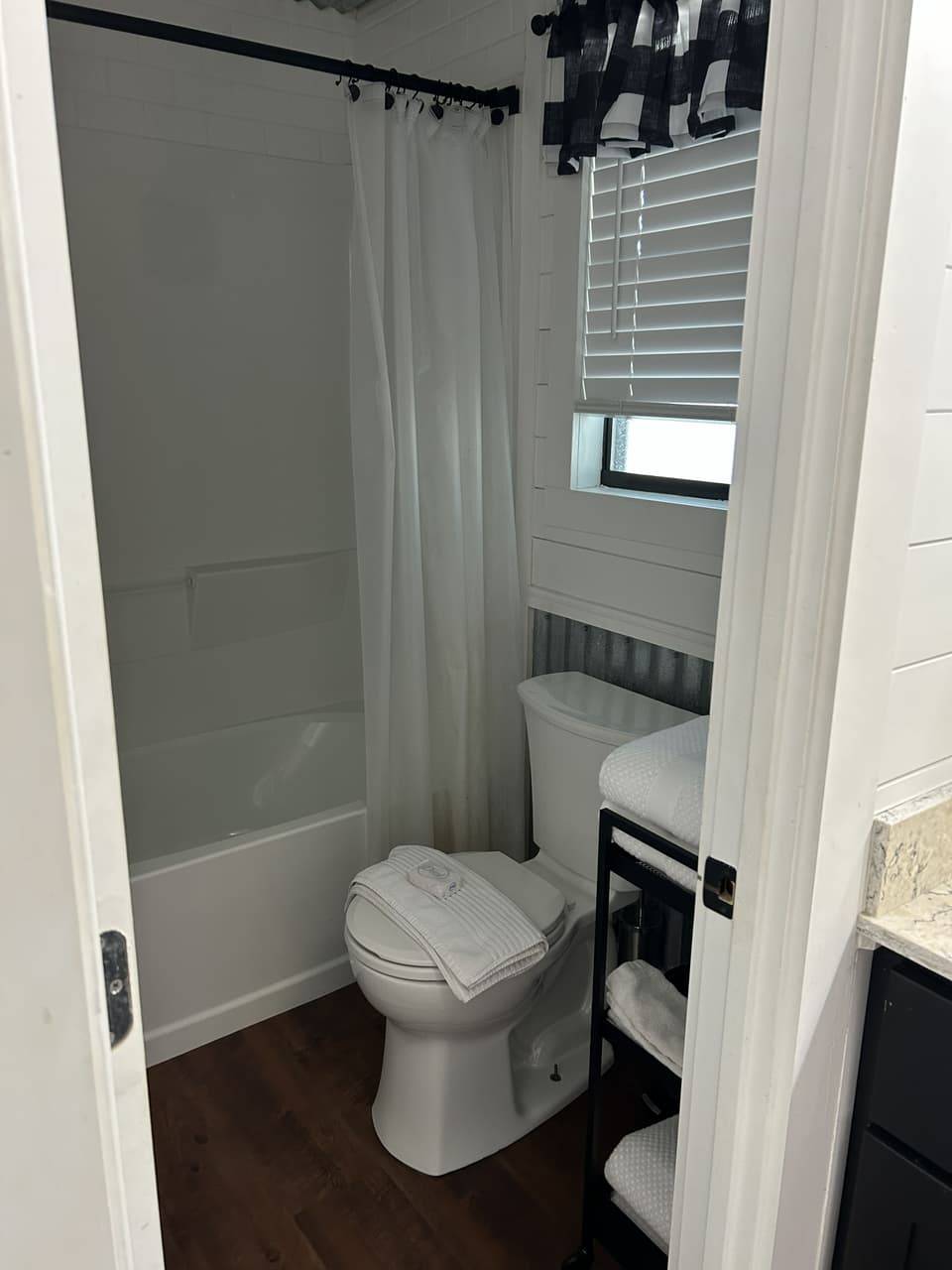 Vanity nook at Sabinal River Lodge with a round mirror, black vanity desk, and buffalo-check curtains