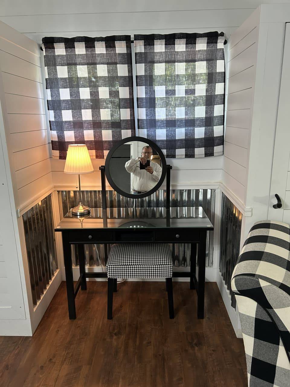 Vanity nook with a round mirror, black vanity desk, and houndstooth stool