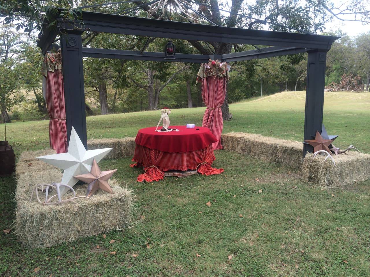 Reception pergola with red gingham curtains, an antler chandelier, and a sweetheart table at Sabinal River Lodge