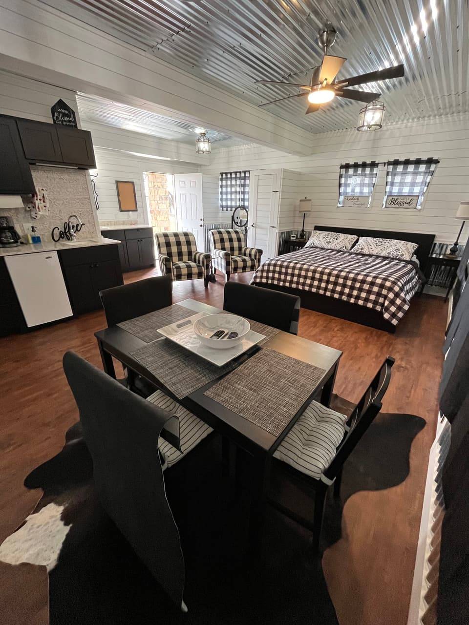 Log-style bedroom at Sabinal River Lodge with two beds, a vaulted beam ceiling, and a glass door to the deck